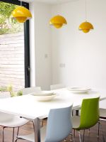 Dining area with colourful chairs and yellow pendant lights