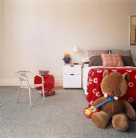 Child's bedroom with teddy bear and grey carpet