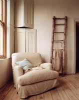 Armchair by window and ladder by wall