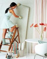 Woman hanging wallpaper on wall