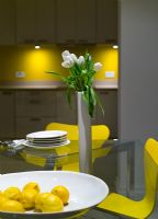 Glass dining table and yellow Jacobsen Series 7 chairs at night