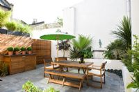 Contemporary patio garden with wooden furniture and green parasol