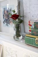 Single red rose in glass vase on mantelpiece