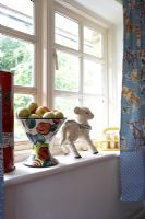 Fruit bowl and ornaments on windowsill 