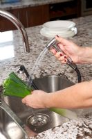 Woman using spray tap to wash vegetables 