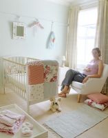 Pregnant woman sitting in baby's nursery 