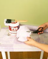 Person cutting wallpaper to cover table 