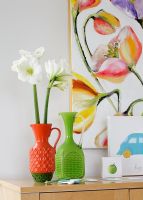 Colourful glass vases on sideboard with floral painting