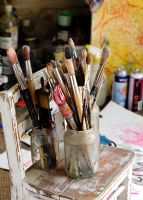 Collection of paint brushes on chair in artist's studio