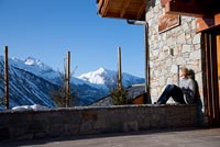 Woman sitting outside chalet with view of Alps