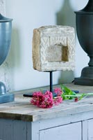 Stone sculpture and sprig of Valerian on sideboard