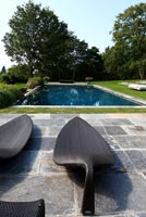 Modern loungers on patio by pool