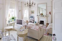 White sitting room with vintage dressing table and linen sofas