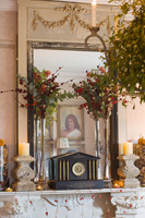 Ornate mantlepiece with french mirror, stone candlesticks and christmas floral displays
