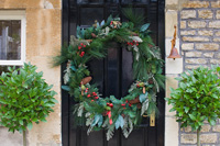 Giant christmas wreath on front door with standard Bay trees
 