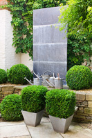 Sculpted lead panel centrepiece, vintage watering cans and Box topiary in pots