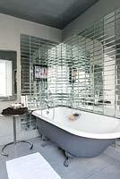Roll top bath surrounded by mirrored tiles