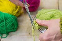 Making christmas pompom decorations - Use the scissors to cut the wool, leaving a wound bundle of wool on the fork 