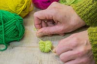 Making christmas pompom decorations - Tie two strong knots to ensure the bundle of wool is kept compacted together