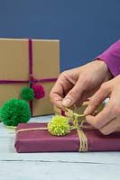 Making christmas pompom decorations - Attaching a wool pompom to a christmas present 