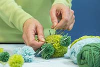 Making a pompom star decoration - Tying wool pompoms to a metal frame in the shape of a star