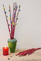Red Cornus stems decorated with miniature wool pompoms