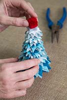 Making a felt christmas tree - Add the pom pom to the top of the tree to finish it off
