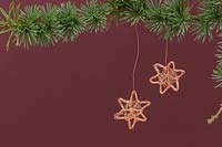 Making copper wire stars - finished decorations hanging from a conifer branch