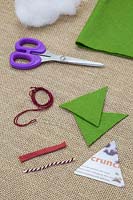 Making stitched felt christmas decorations - Materials required are scissors, felt, needle and thread, wool, triangle template and decorative string