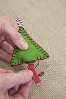 Making stitched felt christmas decorations - Sew a piece of coloured string to the base of the shape