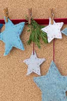 A variety of coloured felt stars hanging against a cork board