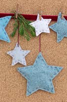 A variety of coloured felt stars hanging against a cork board