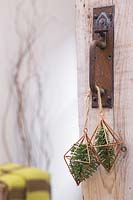 Copper prisms containing pine foliage, hanging from door handle