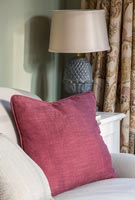 Burgundy cushion on sofa, lamp by Oka