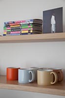 Colourful mugs on wooden shelves