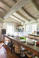 Long wooden island in country kitchen with exposed beams 
