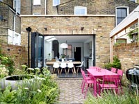 Pink outdoor dining table and view into kitchen through open bi-fold doors 