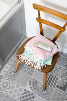 Wooden chair in bathroom with patterned floor tiles 