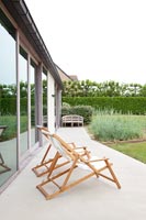 Deck chairs on paved terrace of contemporary home 