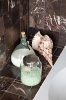 Glassware with sea shell on tiled splashback shelf in bathroom 