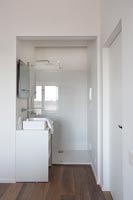 White bathroom with dark wooden floor 