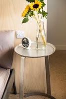 Small circular bedside table and vase of sunflowers  