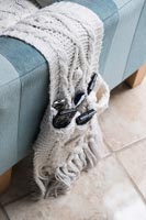 Knitted remote control holder draped over sofa 