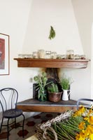 Wooden shelf on chimney breast filled with storage jars and herbs in pots 