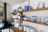 Blue and white crockery on wooden shelf in cottage kitchen 