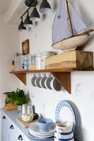 Toy boat and crockery in blue and white cottage kitchen 