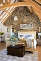 Country bedroom with exposed stone wall and vaulted ceiling 