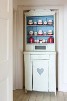 Painted vintage dresser with display of red and white storage jars 