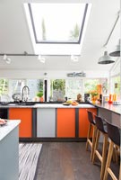 Modern kitchen with grey and orange cabinets and a breakfast bar