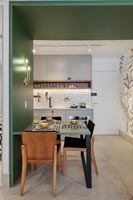 Green wooden frame with built in dining table and view to kitchen 